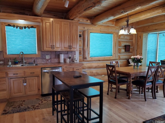 kitchen featuring decorative light fixtures, light countertops, stainless steel dishwasher, a sink, and light wood-type flooring