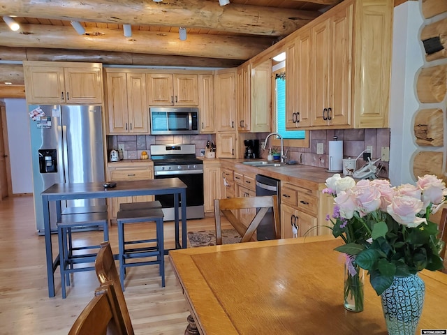 kitchen featuring light brown cabinets, light wood-style flooring, stainless steel appliances, a sink, and light countertops