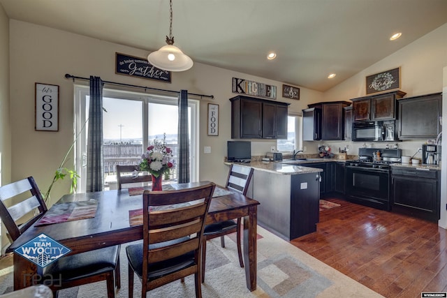 kitchen with dark wood-type flooring, hanging light fixtures, light stone countertops, black appliances, and a sink