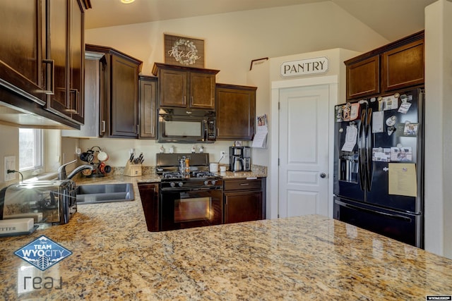 kitchen with black appliances, light stone counters, and a sink