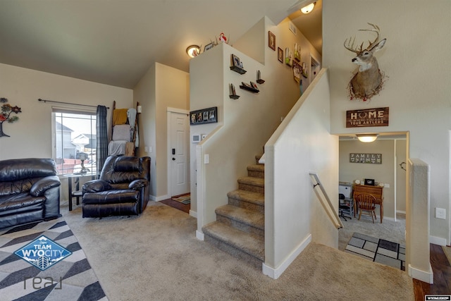 stairs with high vaulted ceiling, carpet flooring, and baseboards