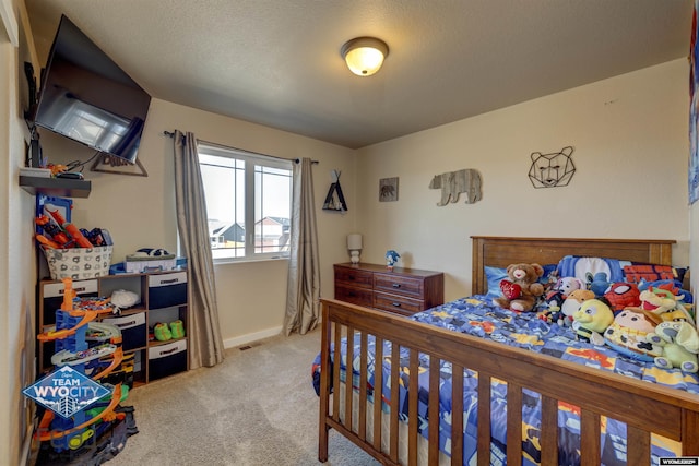 bedroom featuring light carpet, visible vents, baseboards, and a textured ceiling