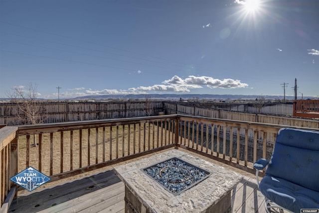 wooden deck with a fenced backyard and a fire pit