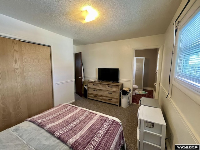 bedroom with a textured ceiling, a closet, and dark carpet