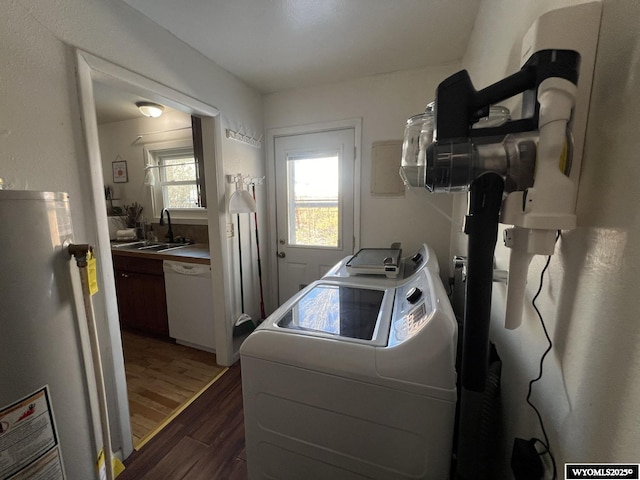 washroom with laundry area, dark wood-type flooring, a sink, water heater, and independent washer and dryer