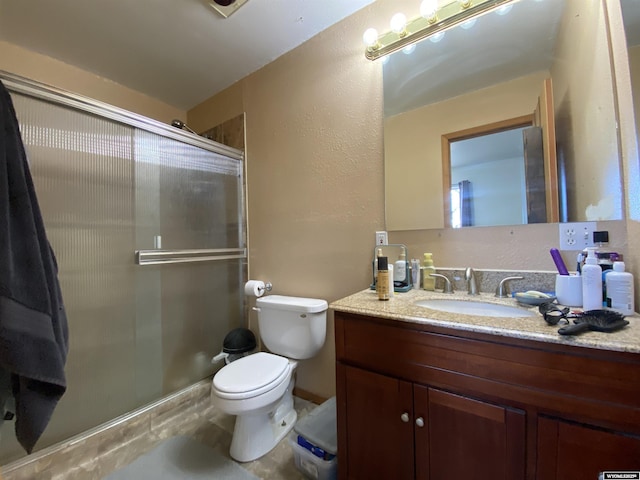 full bath featuring toilet, a textured wall, vanity, and a shower with shower door