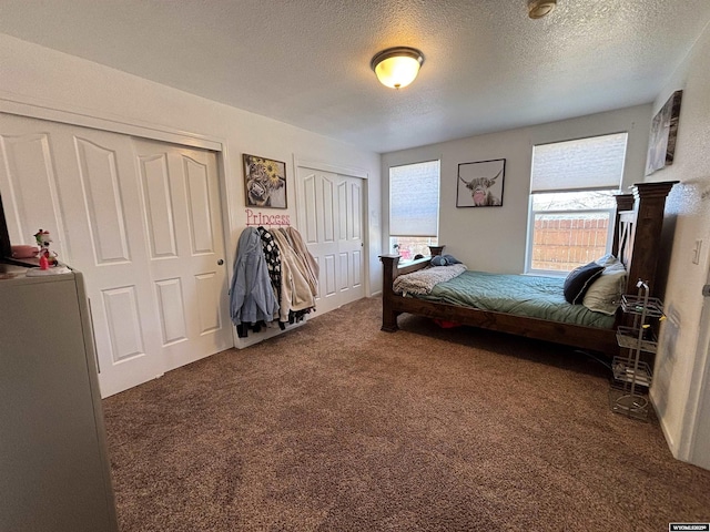 carpeted bedroom featuring a textured ceiling and two closets