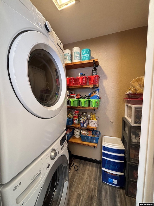 clothes washing area with stacked washer / drying machine, laundry area, and wood finished floors