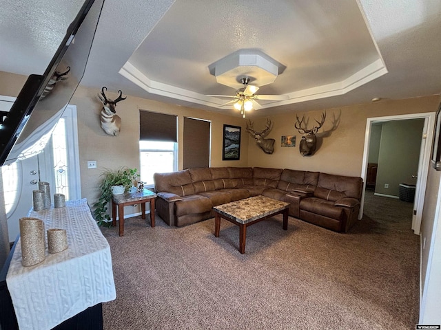 living room with ceiling fan, carpet, a raised ceiling, and a textured ceiling