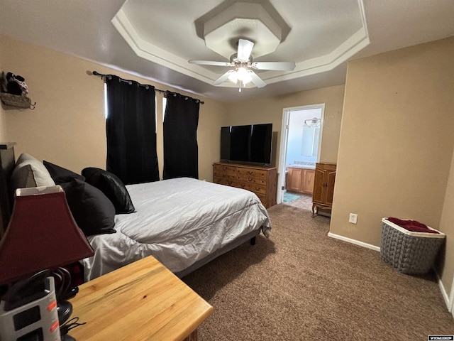 bedroom featuring baseboards, a tray ceiling, carpet flooring, and ensuite bathroom