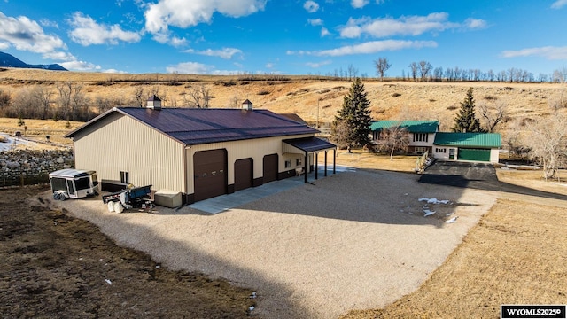 view of front of home featuring an outbuilding, metal roof, a rural view, a garage, and a chimney