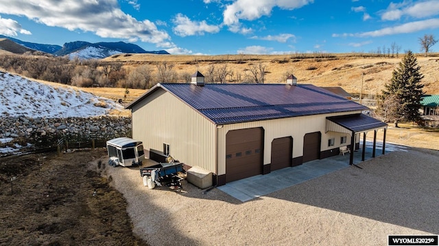 exterior space featuring a garage, metal roof, a chimney, and a mountain view