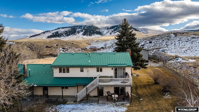 back of house with a chimney, stairway, metal roof, a deck with mountain view, and a patio area