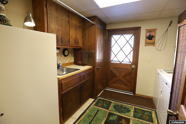 kitchen with washing machine and clothes dryer, tasteful backsplash, light countertops, a sink, and a drop ceiling