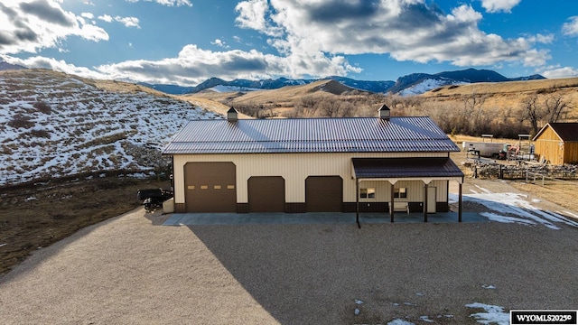 view of front of home with metal roof, a mountain view, a chimney, and a detached garage