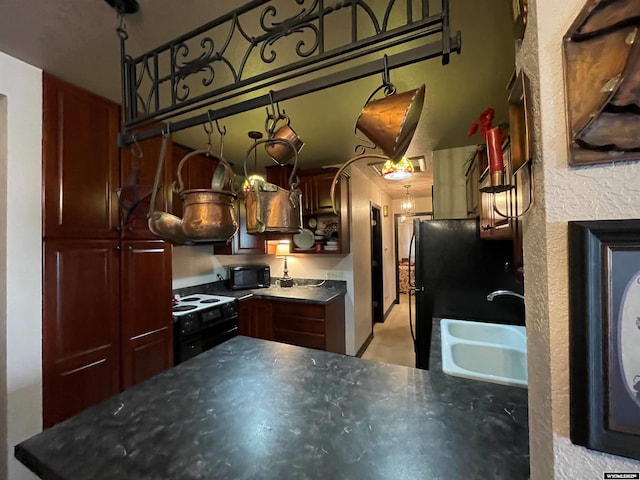 kitchen featuring black appliances, dark countertops, and a sink