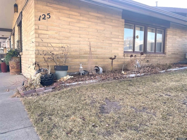 view of side of property featuring a lawn and brick siding