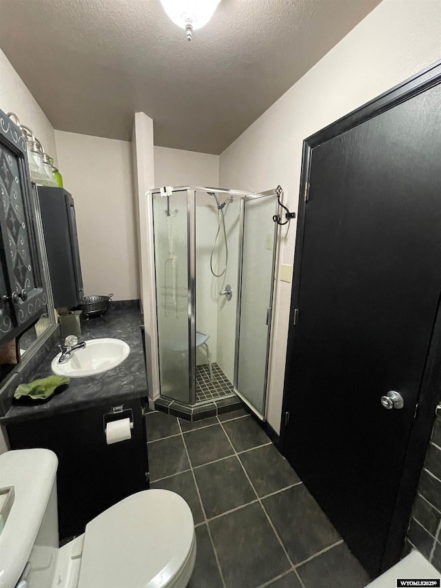 full bathroom featuring toilet, a textured ceiling, a shower stall, vanity, and tile patterned floors