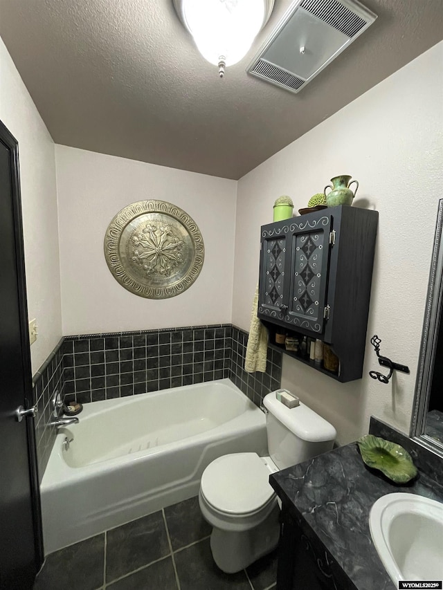 bathroom with a textured ceiling, toilet, visible vents, a bath, and tile patterned floors