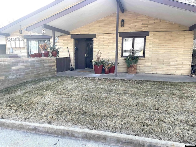 entrance to property featuring brick siding and a lawn