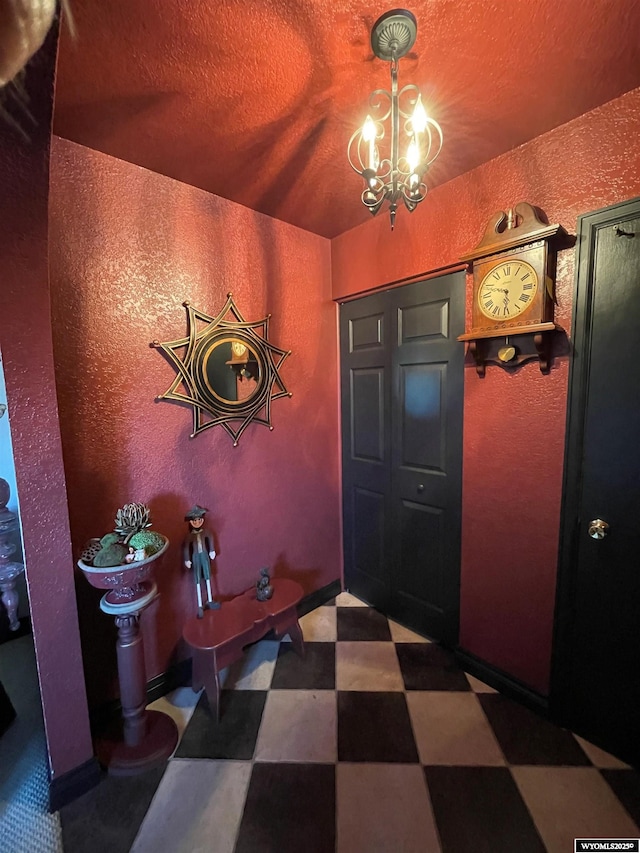 entrance foyer with dark floors, a chandelier, a textured ceiling, and a textured wall