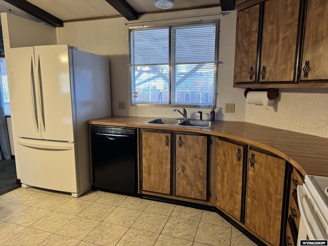 kitchen with black dishwasher, a textured wall, freestanding refrigerator, a sink, and beamed ceiling