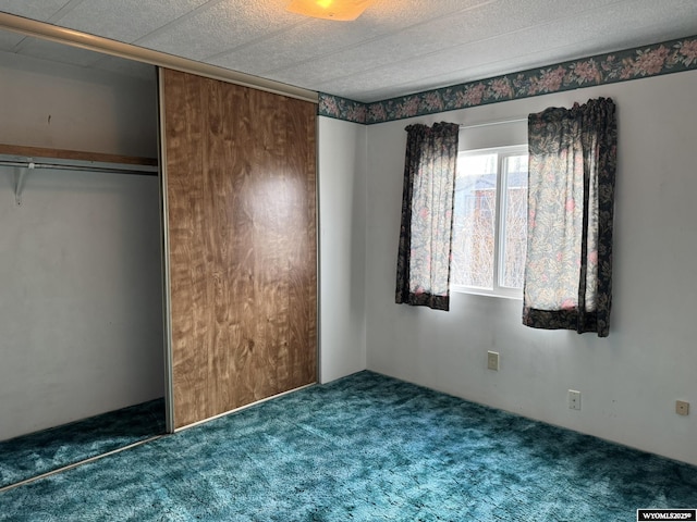 unfurnished bedroom featuring dark colored carpet and a closet