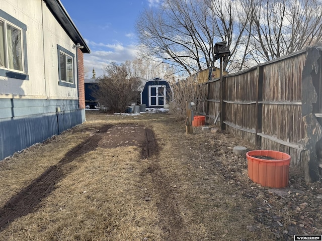 view of yard with a shed, fence, and an outbuilding