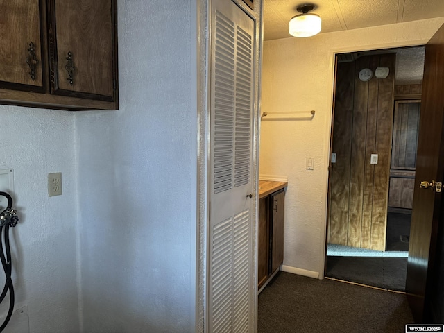 interior space with dark brown cabinets, dark carpet, and baseboards