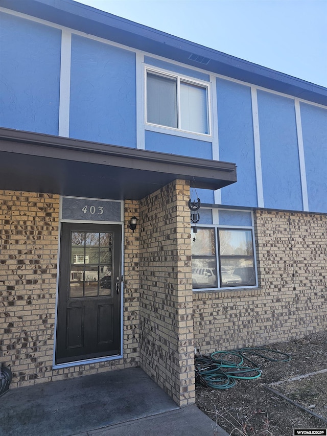 view of exterior entry featuring brick siding