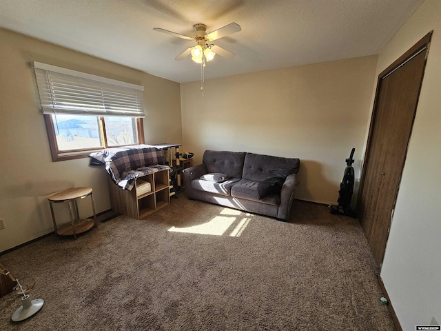 living room featuring ceiling fan, a textured ceiling, dark carpet, and baseboards