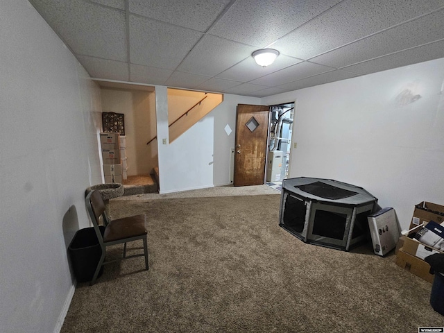 living area featuring carpet floors, stairs, baseboards, and a drop ceiling