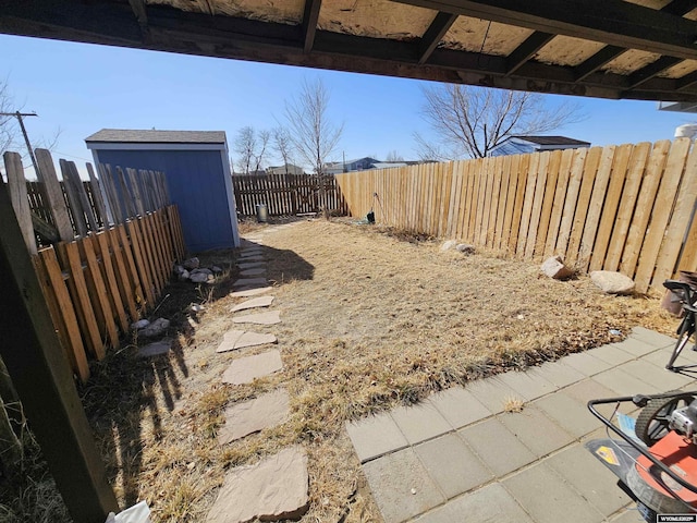 view of yard featuring an outbuilding, a patio, a shed, and a fenced backyard