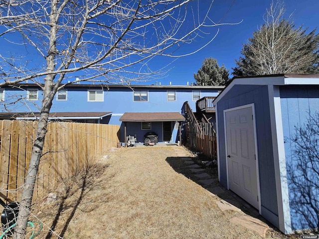 rear view of property with an outdoor structure, fence, and a shed