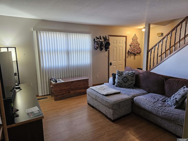 living area featuring stairway, a textured ceiling, and wood finished floors