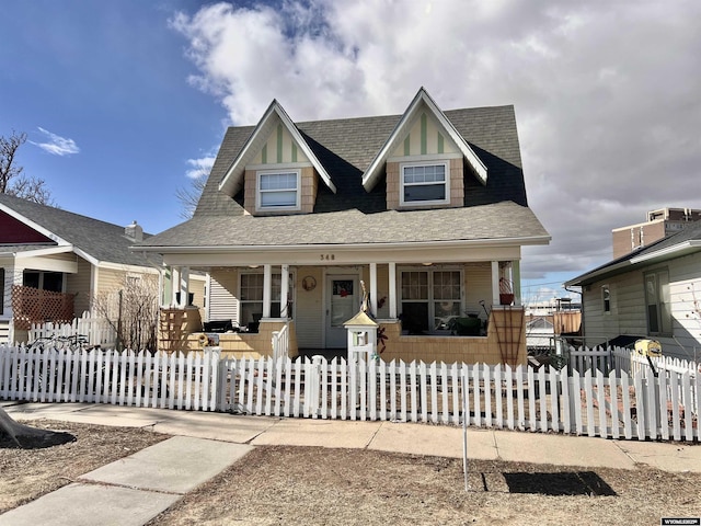 view of front of property featuring covered porch, a fenced front yard, and roof with shingles