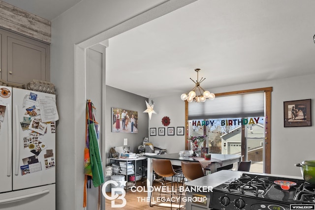 kitchen with gray cabinetry, wood finished floors, a notable chandelier, and freestanding refrigerator