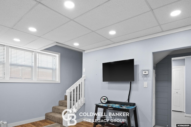 interior space featuring a paneled ceiling, recessed lighting, wood finished floors, baseboards, and stairway