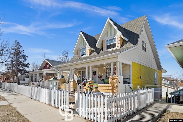 view of front of property featuring covered porch, a fenced front yard, a residential view, and roof with shingles