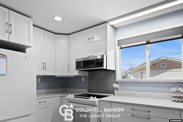 kitchen featuring white cabinets, white appliances, and light countertops