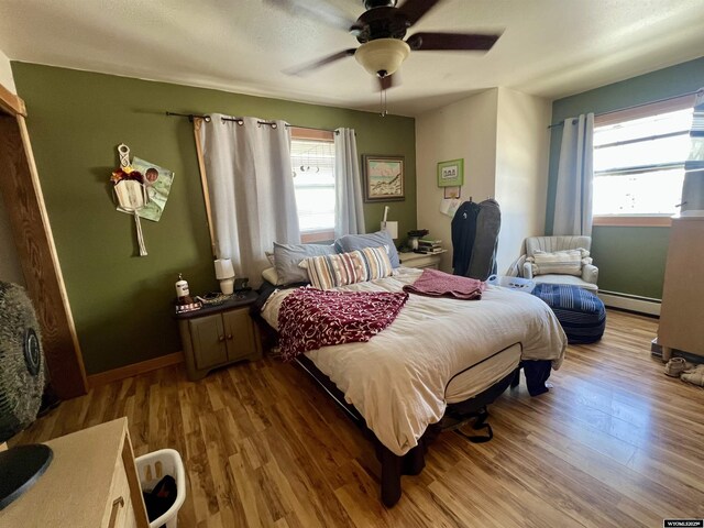 bedroom with baseboards, ceiling fan, baseboard heating, and wood finished floors