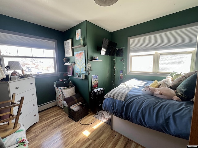 bedroom featuring light wood finished floors and baseboard heating