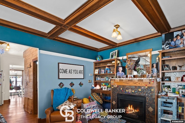 living area featuring coffered ceiling, a tiled fireplace, wood finished floors, and beam ceiling