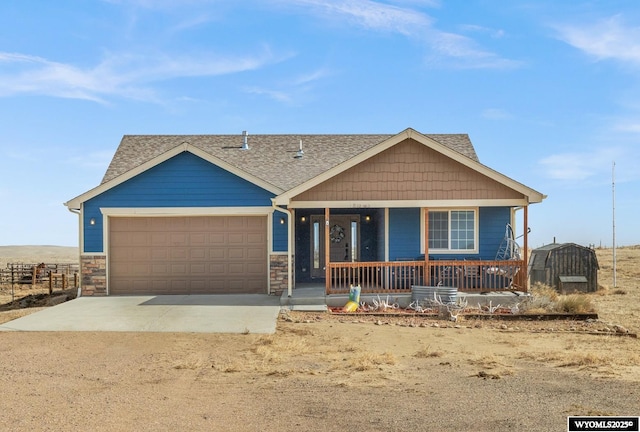 view of front of property featuring a garage, covered porch, dirt driveway, and roof with shingles