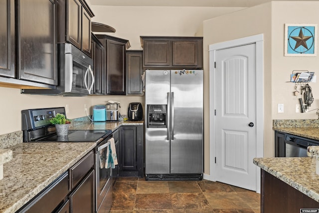 kitchen with dark brown cabinets, appliances with stainless steel finishes, stone finish flooring, and light stone countertops