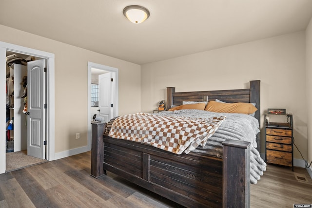 bedroom featuring a spacious closet, wood finished floors, and baseboards