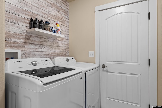 washroom featuring laundry area, separate washer and dryer, and wood walls