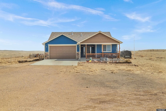 view of front facade featuring covered porch, fence, a garage, stone siding, and driveway