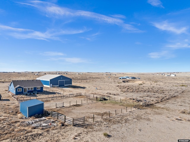 view of yard featuring view of desert, a pole building, an outdoor structure, and fence