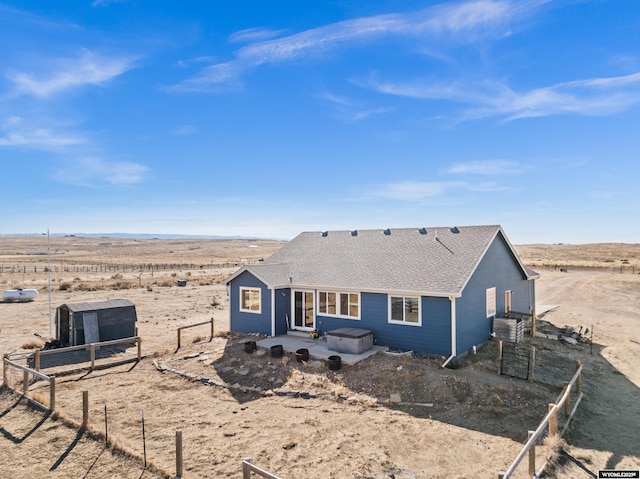 back of house with a shingled roof and fence